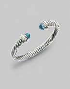 From the Silver Classics Collection. The signature Yurman cable bangle, capped with faceted blue topaz domes and accents of 14k gold. Blue topaz Sterling silver and 14k yellow gold Cable, 7mm Diameter, about 2¼ Imported