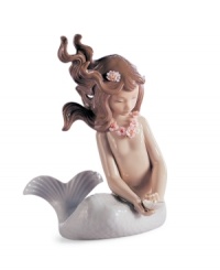 The world is her oyster. A pretty young mermaid treasures a shiny pearl in this fanciful porcelain figurine from under the sea, handcrafted by Lladro.