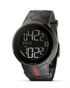 From the I-Gucci collection, a modern timepiece. Black bezel casing frames a round black dial that offers the option of a digital or analog display. White digits represent hour, minute, second, date and your location. Black rubber strap with red/green webbing accent. Triple deployment buckle.