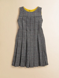 A retro, school-girl design in houndstooth goes modern with colorful piping at the neckline. Houndstooth patternRound neckline with contrast pipingSleevelessPleated bodice and skirtFit and flare silhouetteBack button closure50% fleece wool/50% viscoseMachine washMade in Italy