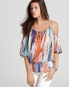 A billowy silhouette, cutout shoulders and abstract print infuse this eclectic GUESS top with carefree summer style.