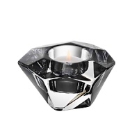 Shimmering facets and an asymmetrical design give this hand-cut, glistening crystal votive a shimmering, jewel-like look.