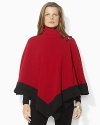 A classic wool poncho updated with striking leather buckles and a fierce color-blocked hemline.