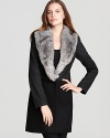 Take a refined walk on the wild side as a plush faux-fur collar adorns a sumptuous DKNY coat for chic exoticism.