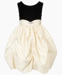 A classic silhouette is highlighted by a billowing champagne-colored skirt that will have her looking her regal best.