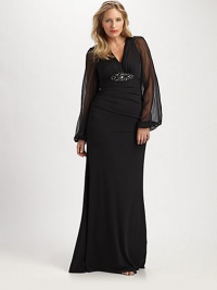 This stunning gown was designed to accentuate your shape, thanks to a striking embellishment at a subtly gathered bust and sheer sleeves offering glamorous arm coverage.V-necklineSheer, bell sleevesEmbellishment at gathered bustConcealed back zipperFully linedAbout 45 from natural waist95% polyester/5% spandexDry cleanMade in USA of imported fabric