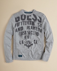 GUESS cotton crewneck pullover adds edge with allover stencil logo print.