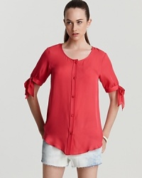 Show off your sweet side in this silk MARC BY MARC JACOBS top with coquettish bow ties at the sleeves. In the season's of-the-moment coral hue with matching buttons through the front, the chic look elevates denim cut-offs for cabana perfection.