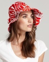 A vibrant patterned twill hat with large brim and large bow detail at side.