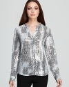 Subtle sequins enliven a snakeskin-print Calvin Klein blouse for a riveting style choice. Play up the tonal palette with sleek sliver accents and embrace untamed glamour.