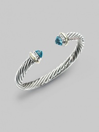 From the Silver Classics Collection. The signature Yurman cable bangle, capped with faceted blue topaz domes and accents of 14k gold. Blue topaz Sterling silver and 14k yellow gold Cable, 7mm Diameter, about 2¼ Imported