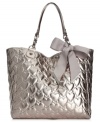 Let your look shine day and night with this shimmery metallic tote from Betsey Johnson. Spacious, pocked-lined and adorned with a sweet heart-embossed pattern topped off with a bow, it's truly scrumptious.