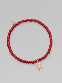 The hamsa, a traditional protective amulet, is encrusted with diamonds and accented with one ruby as it hangs from a stretchy strand of richly colored coral beads. Diamonds, 0.05 tcw Coral 14k yellow gold Diameter, about 2 (unstretched) Charm length, about ½ Imported