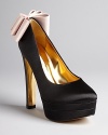 Fancy goes fantastic in these bold evening platform pumps featuring golden heel accents and oversized contrast bows that take this look over the top. They're perfect with a little black cocktail dress.