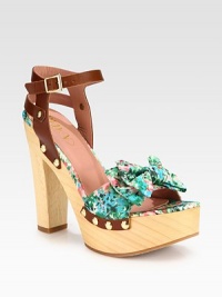 A dimensional bow tops this clog-inspired design with a powerful wooden heel and platform. Wooden heel, 5¼ (130mm)Wooden platform, 1¾ (45mm)Compares to a 3½ heel (90mm)Nylon and leather upper with metal studsAdjustable ankle strapLeather liningRubber solePadded insoleMade in Italy