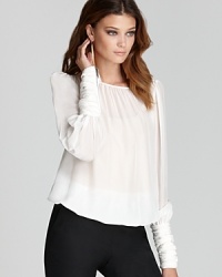 An airy Rachel Zoe silk blouse makes a modern statement with ruched cuffs touting exposed zip detail. The ideal way to add edge to suit separates, the silhouette takes office looks from day to night with finesse.