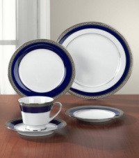 Formal white fine china dinner plates from Noritake display a dramatic combination of scrolling leaves on shimmering platinum and an inner band of intense cobalt blue. Dishwasher safe.