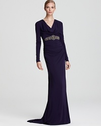 A jeweled waistband lends brilliance to a standout cowl neck gown from Badgley Mischka, rendered in a royal purple hue.