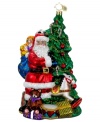 The epitome of holiday cheer. Santa Claus stops unloading gifts to smile beside a beautifully decorated Christmas Tree in this elaborately hand-painted ornament from Christopher Radko.