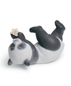 Panda at play! A lovable black and white bear tumbles onto his side, pawing at a single bloom in Lladro's artfully crafted porcelain figurine.