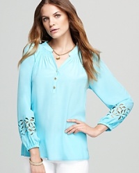 Intricate floral cutouts lend a touch of bohemian flair to a billowing silk Lilly Pulitzer blouse.