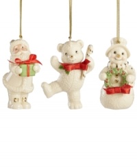 A set of three happy-go-lucky ornaments decorate your tree, featuring Santa Claus, a teddy bear and a snowman with gold embellishments and red ribbon bows. Crafted of porcelain from Lenox.