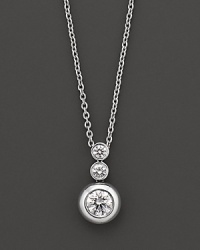 White gold bezel-set diamond necklace in three-stone drop design. With signature ruby accent. Designed by Roberto Coin.